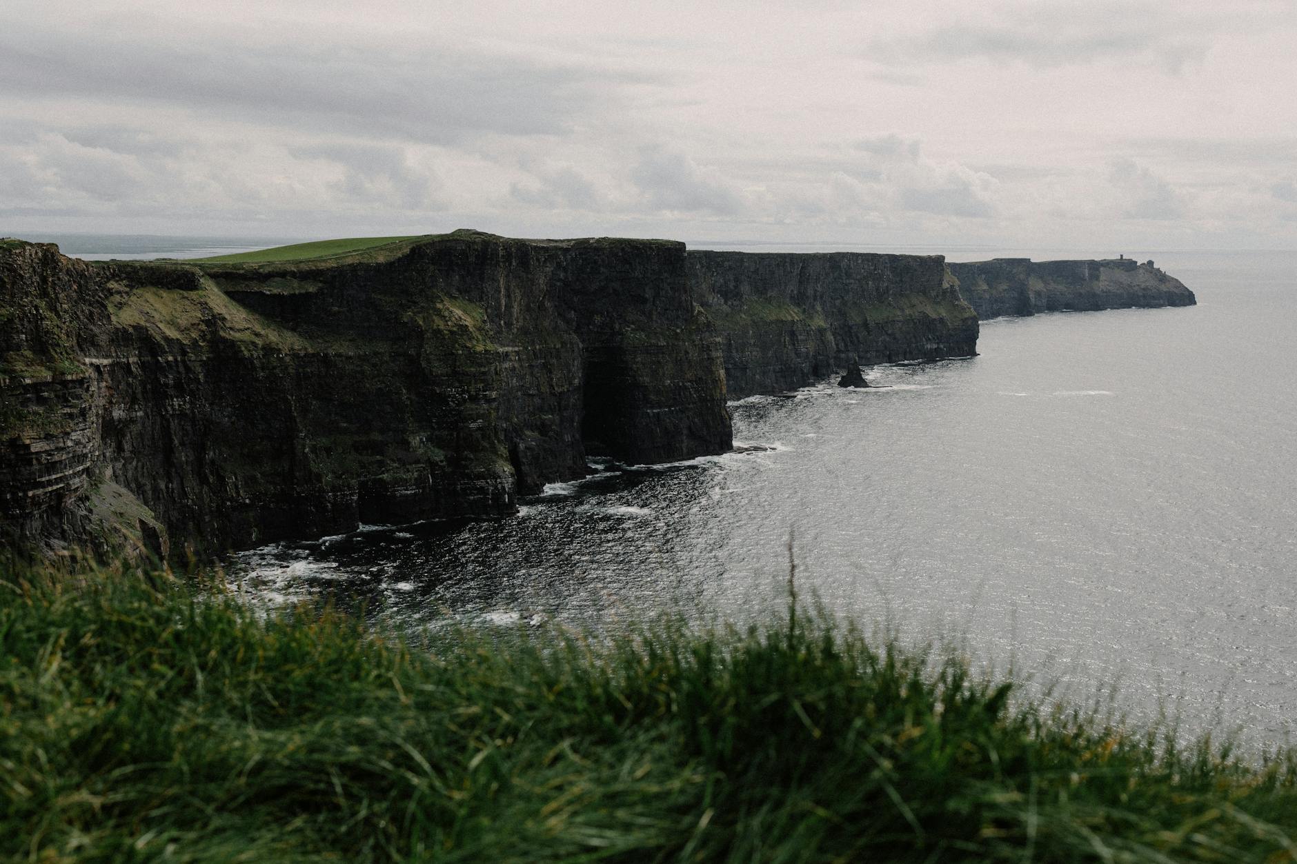 Klify Moheru w Irlandii nad oceanem pod pochmurnym niebem