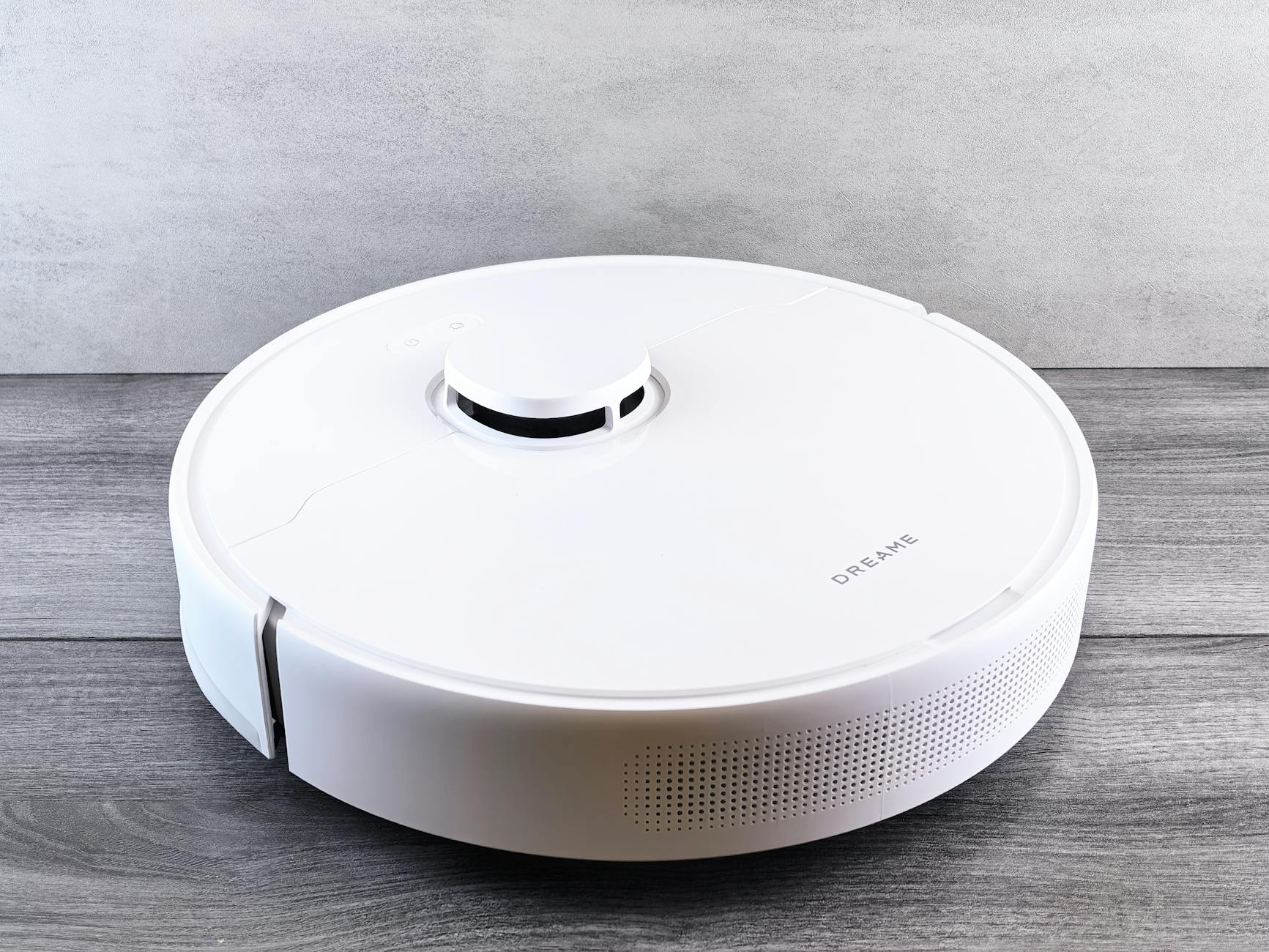 Biały robot sprzątający na drewnianej podłodze w inteligentnym domu
