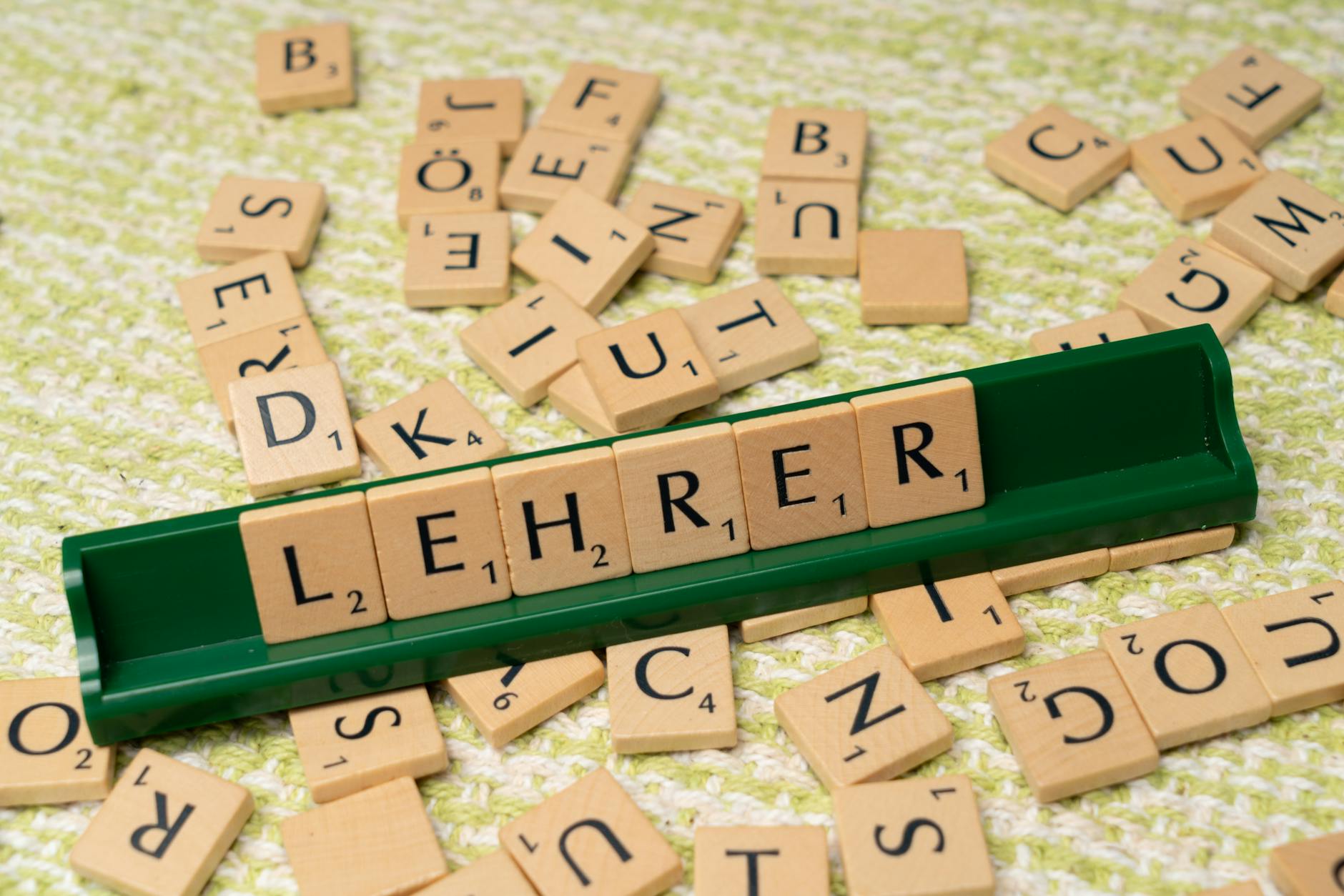 Kafelki z literami tworzące słowo Lehrer na stojaku, wokół rozsypane litery