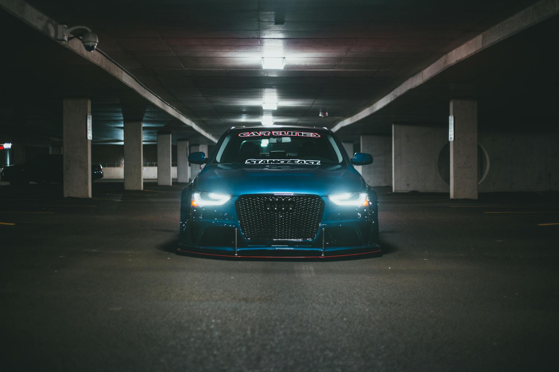 Niebieski samochód zaparkowany w jasno oświetlonym garażu