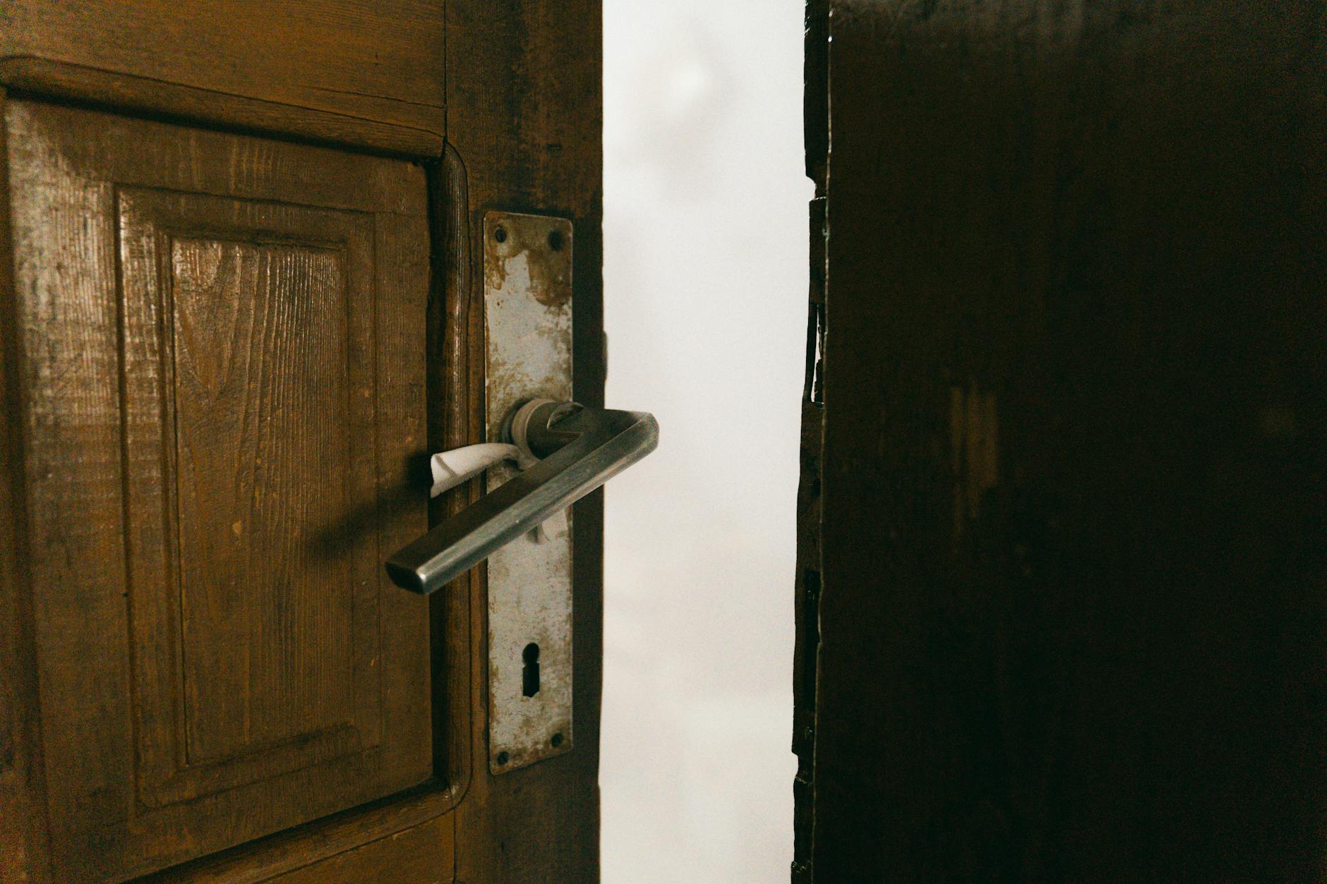 Drewniane uchylone drzwi balkonowe z metalową klamką