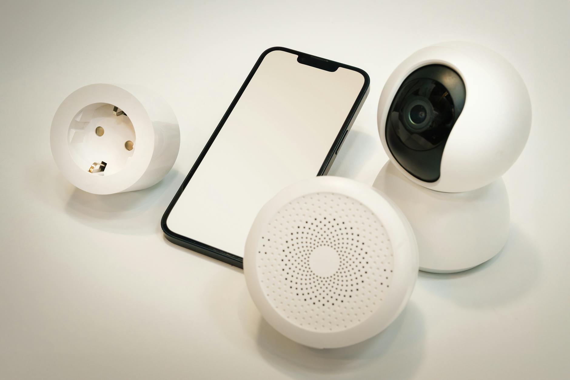 Urządzenia smart home: kamera, głośnik i smartfon na białym tle