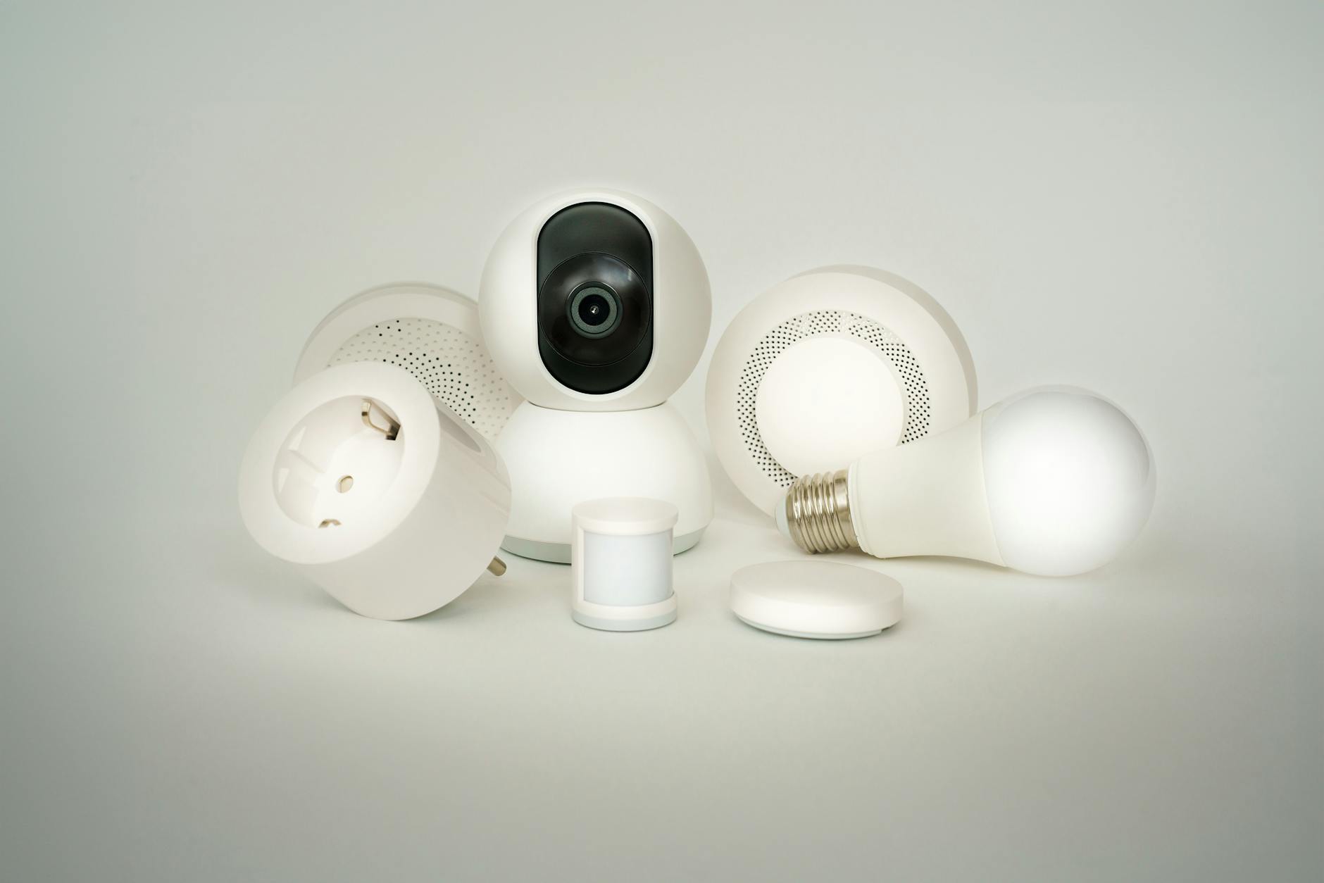 Urządzenia smart home: żarówki, gniazdka i kamery na białym tle