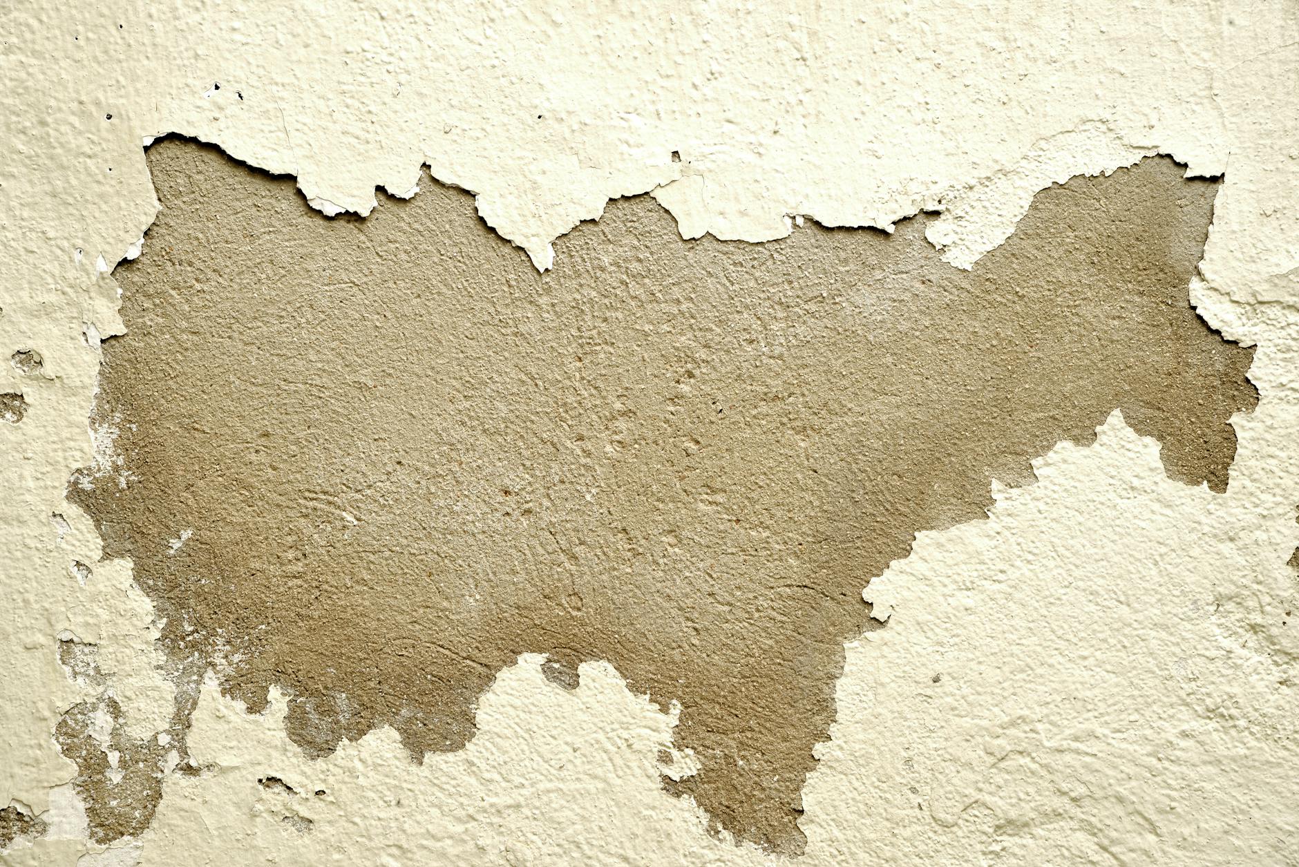 Zbliżenie ściany z odłażącą farbą i chropowatym podłożem