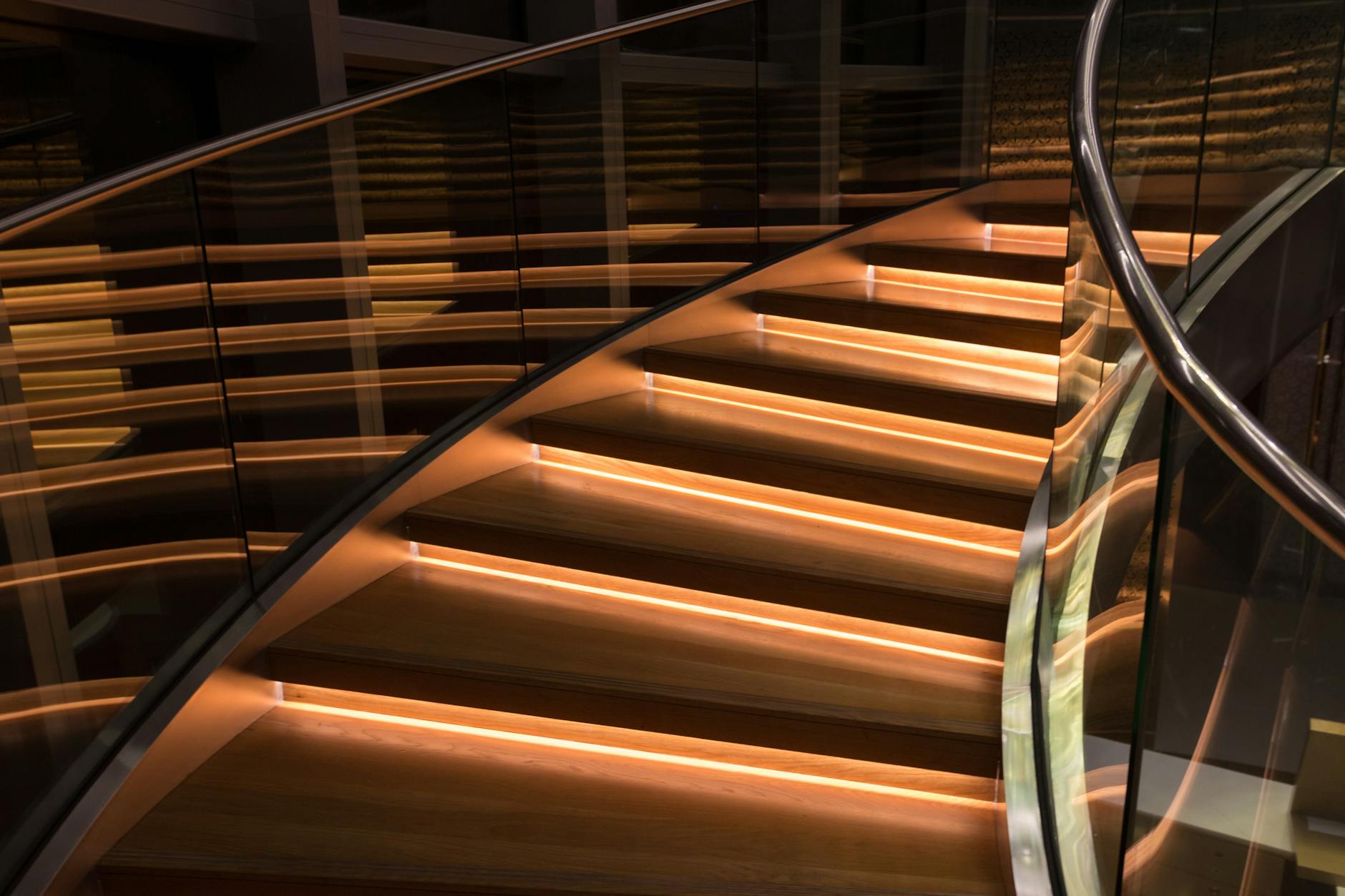 Kręte schody z balustradą szklaną i eleganckim oświetleniem LED