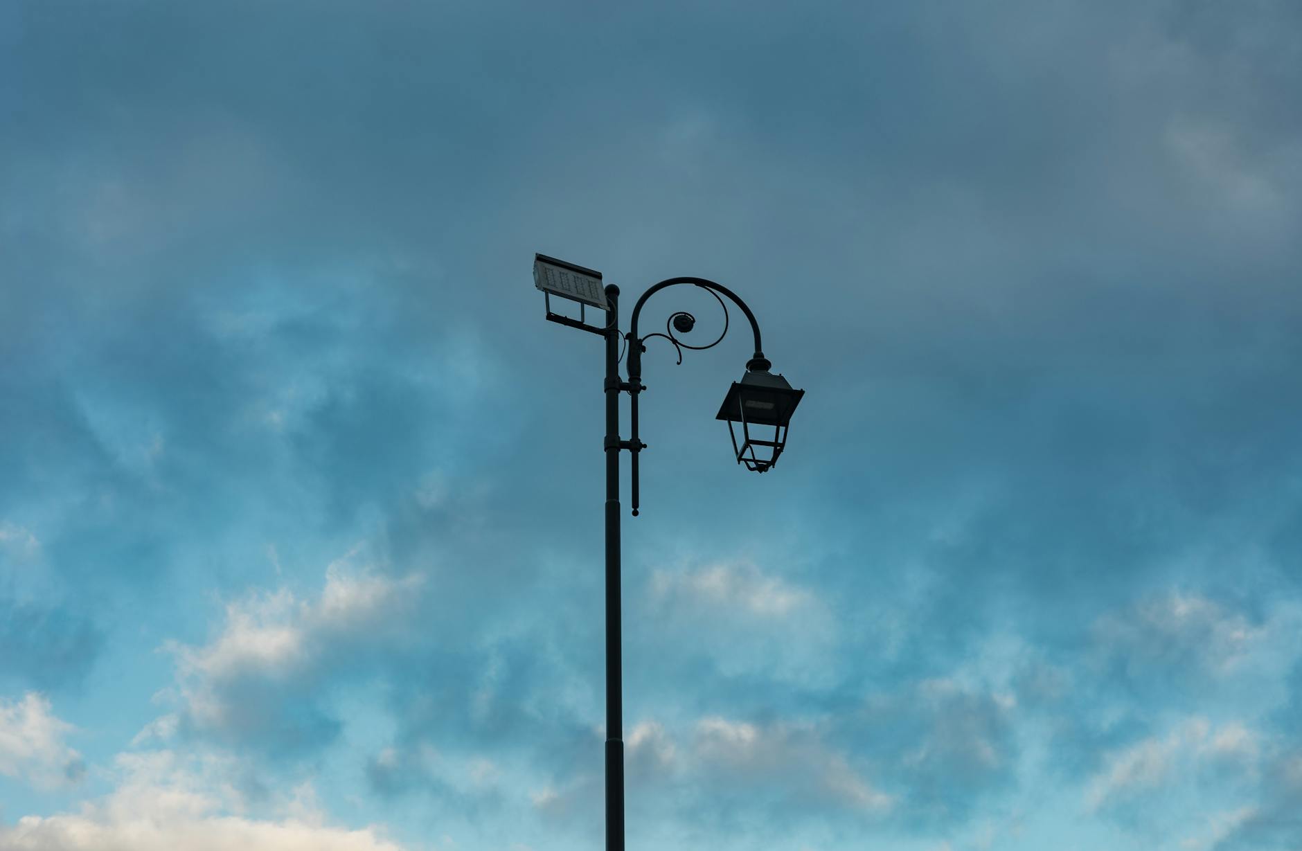 Solarny kinkiet uliczny na tle burzowego nieba we włoskim miasteczku