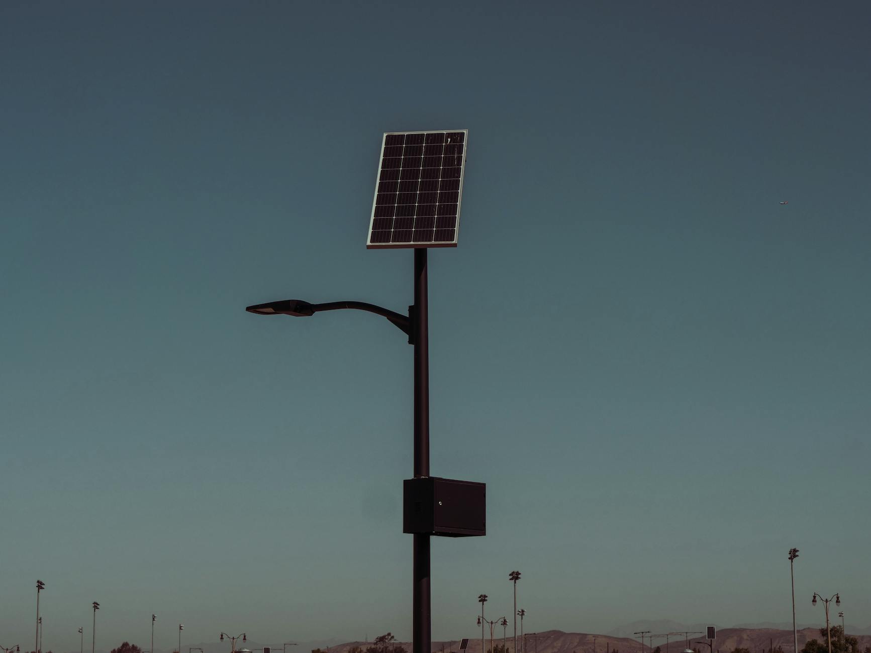 Uliczna lampa solarna z osobnym panelem na tle wieczornego nieba